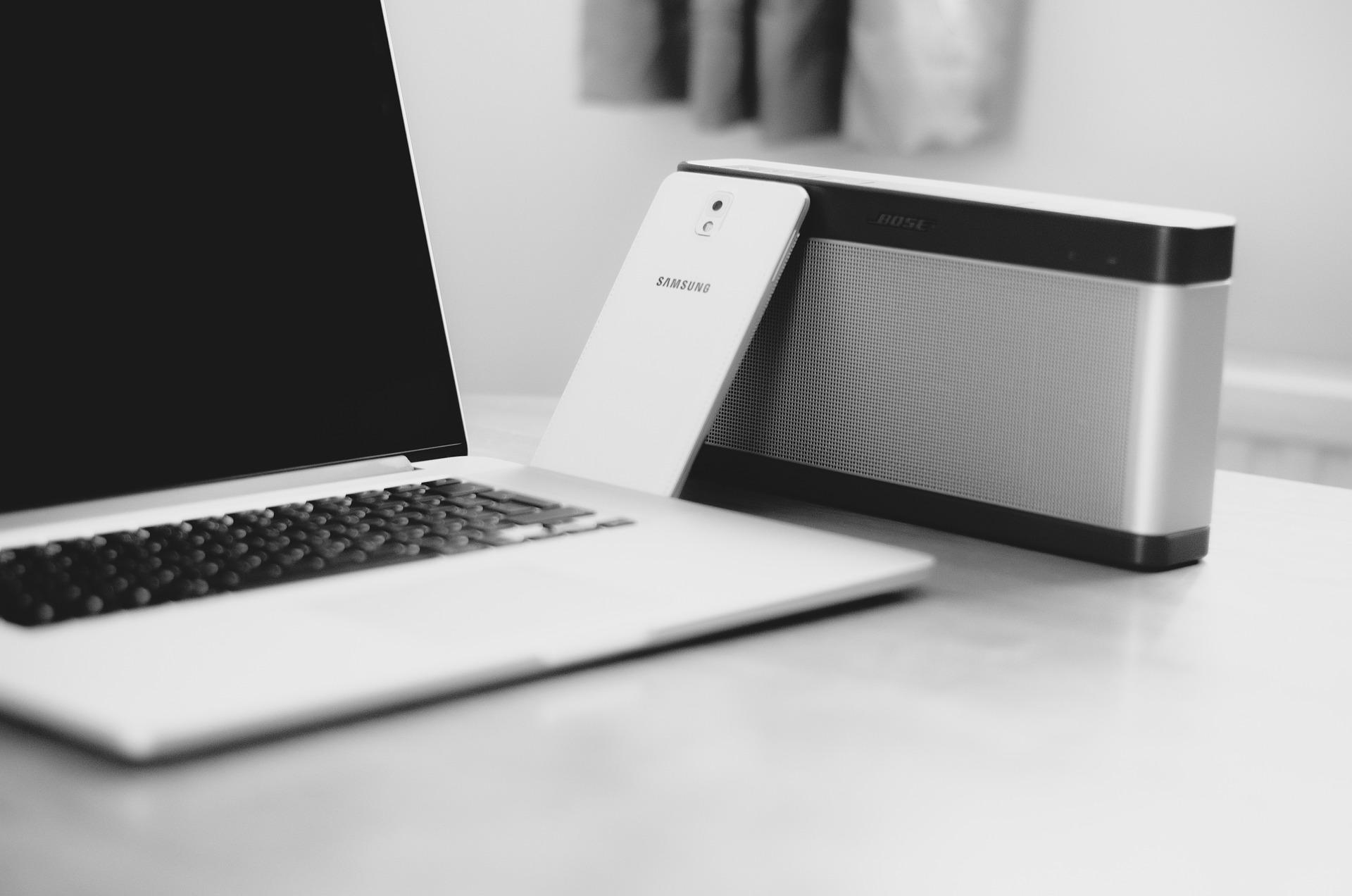 Widoczny fragment laptopa oraz telefonu komórkowego. Zdjęcie w czarno-białej kolorystyce (odpowiedzialność pracownika za mienie firmy)