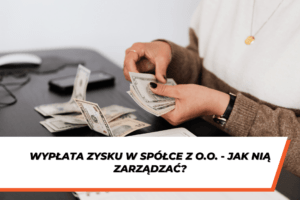 Osoba siedząca przy biurku liczy banknoty w dolarach amerykańskich, trzymając plik pieniędzy w dłoni. Na biurku leżą rozłożone banknoty oraz telefon. Na dole grafiki znajduje się pasek z napisem: ‘Wypłata zysku w spółce z o.o. – jak nią zarządzać?